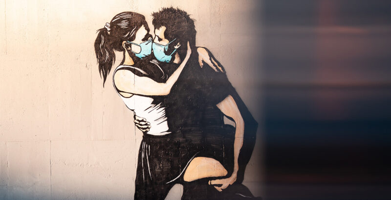 Graffiti eines Paares, das sich mit Mund-Nasen-Schutz küsst.