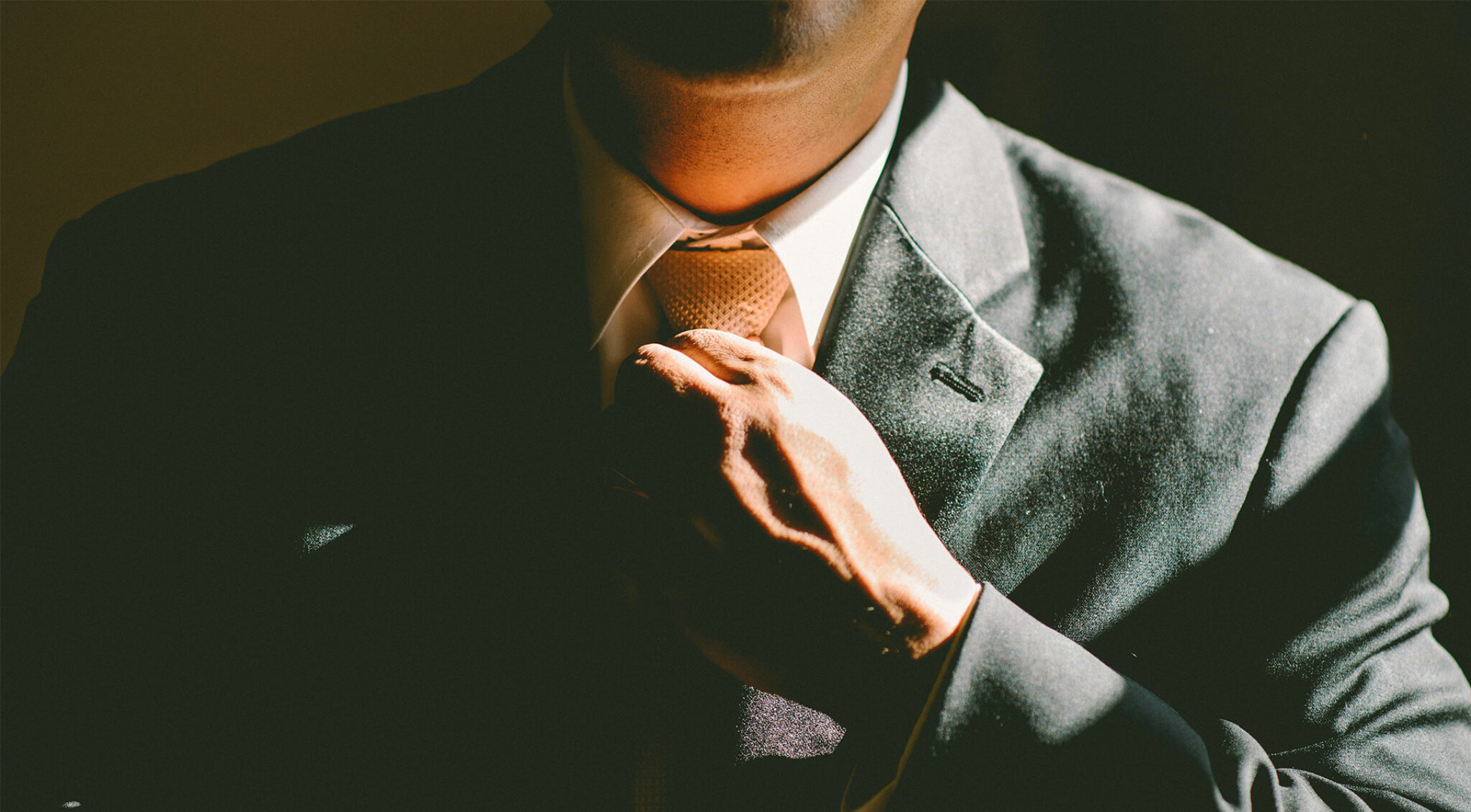 Ein Mann im Anzug richtet seine Krawatte.