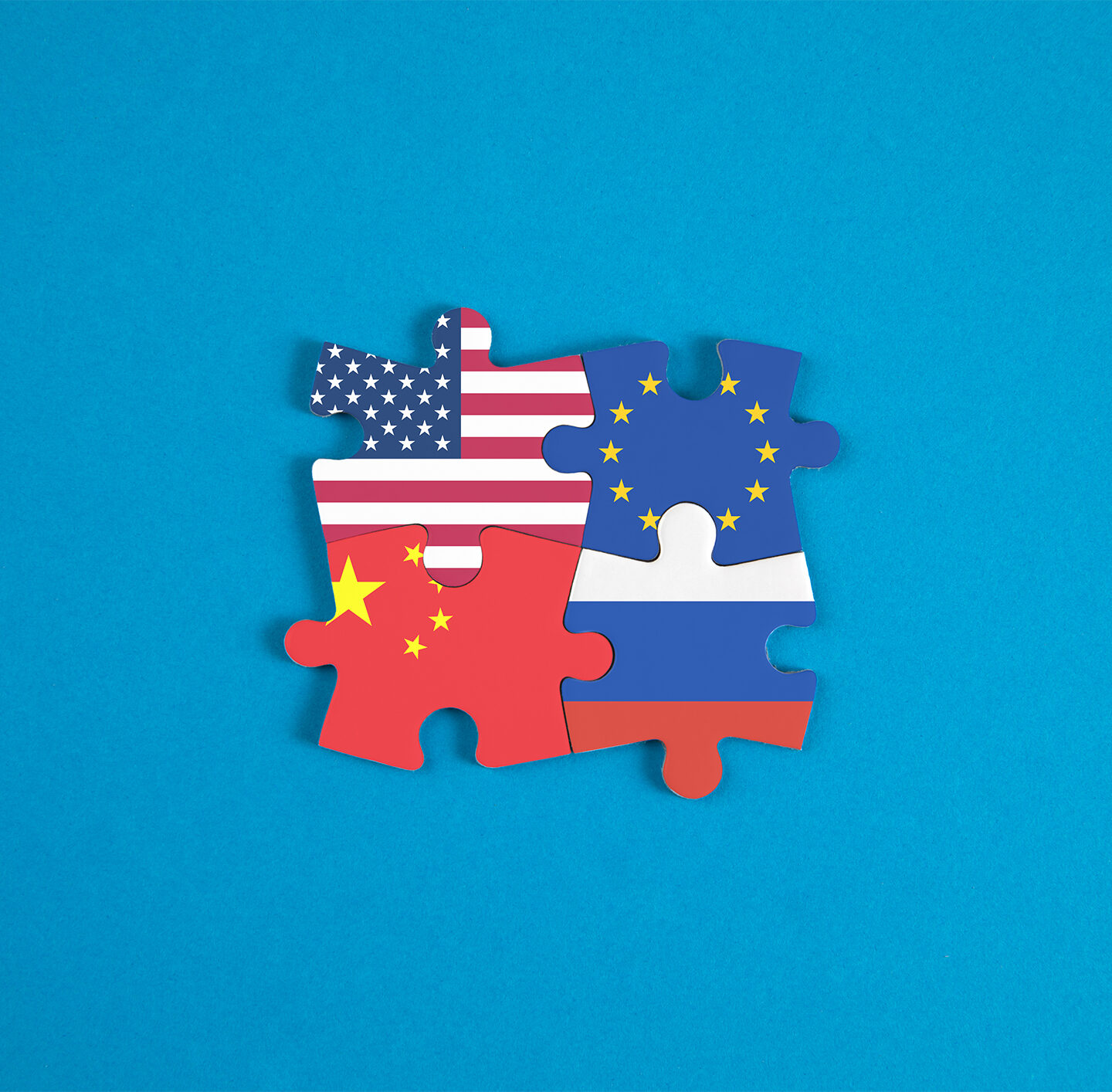 Die Flaggen der USA, China, Europa und Russland als Puzzleteile ineinander gesteckt.