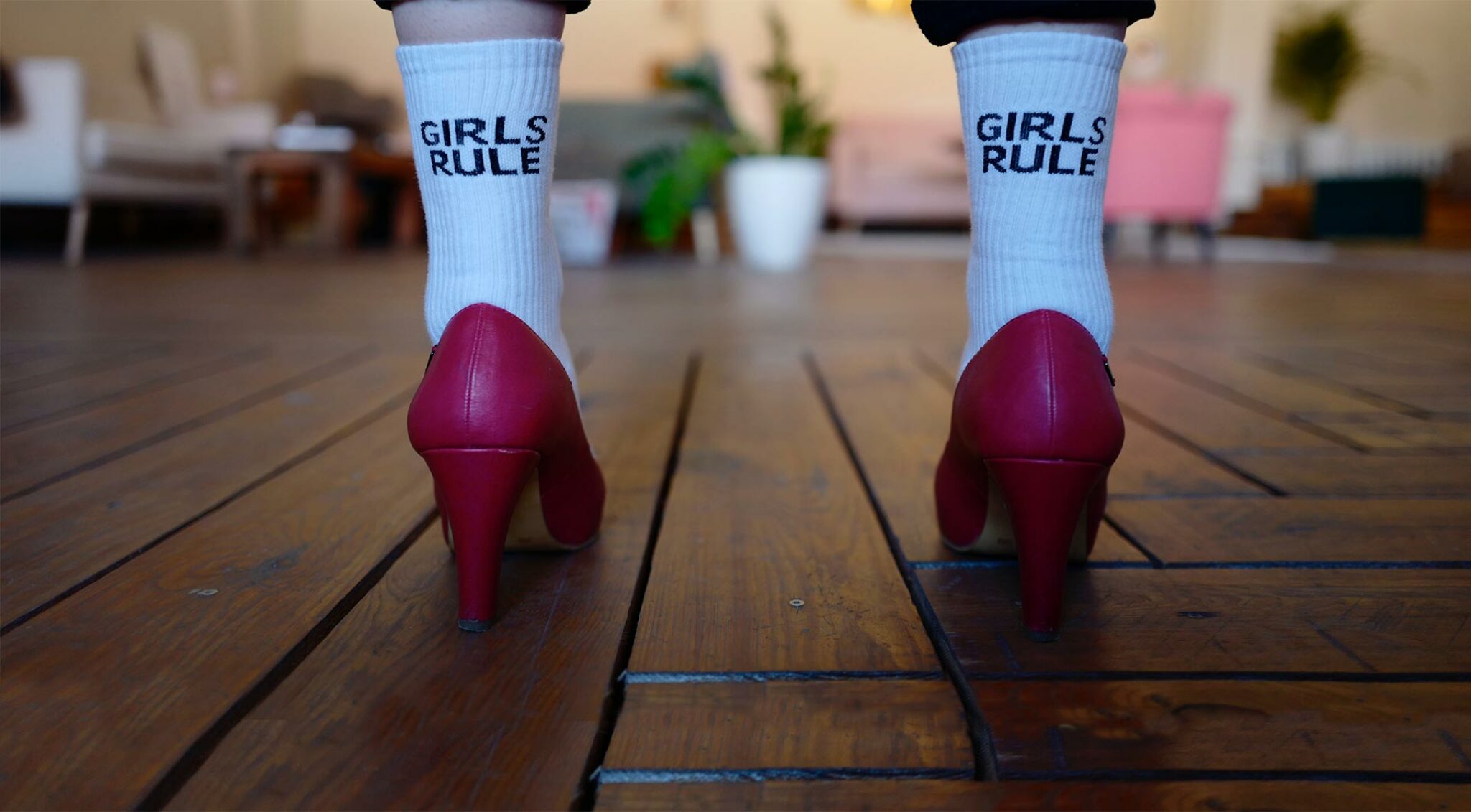 Frau in pinken High Heels trägt Socken mit Aufschrift "Girls rule".