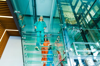 Mitarbeiterinnen eines Krankenhauses laufen einen Gang entlang.