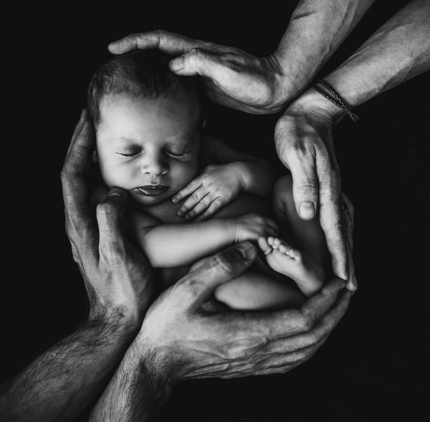 Neugeborenes, umrahmt von den Händen der Eltern.