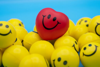Viele gelbe und ein roter Ball, mit glücklichen, aufgemalten Gesichtern.