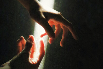 Zwei Hände werden von einem Lichtstrahl beleuchtet.