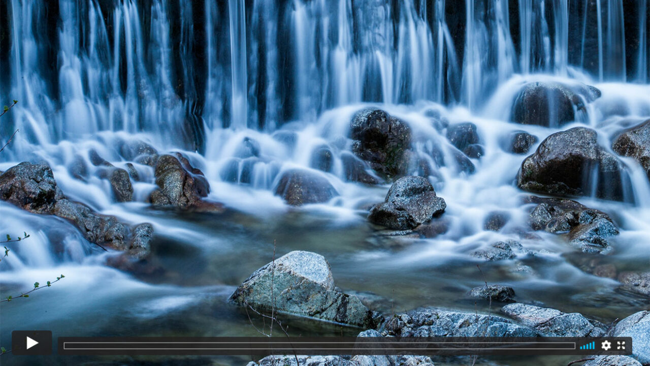 Steine vor einem mystisch anmutenden Wasserfall.
