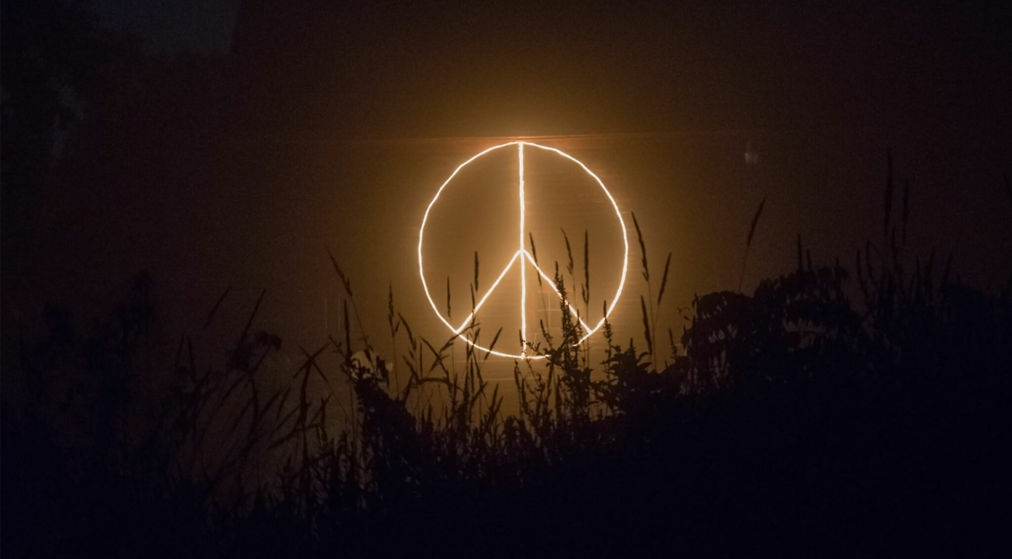 Leuchtendes Peace-Zeichen in der Nacht.