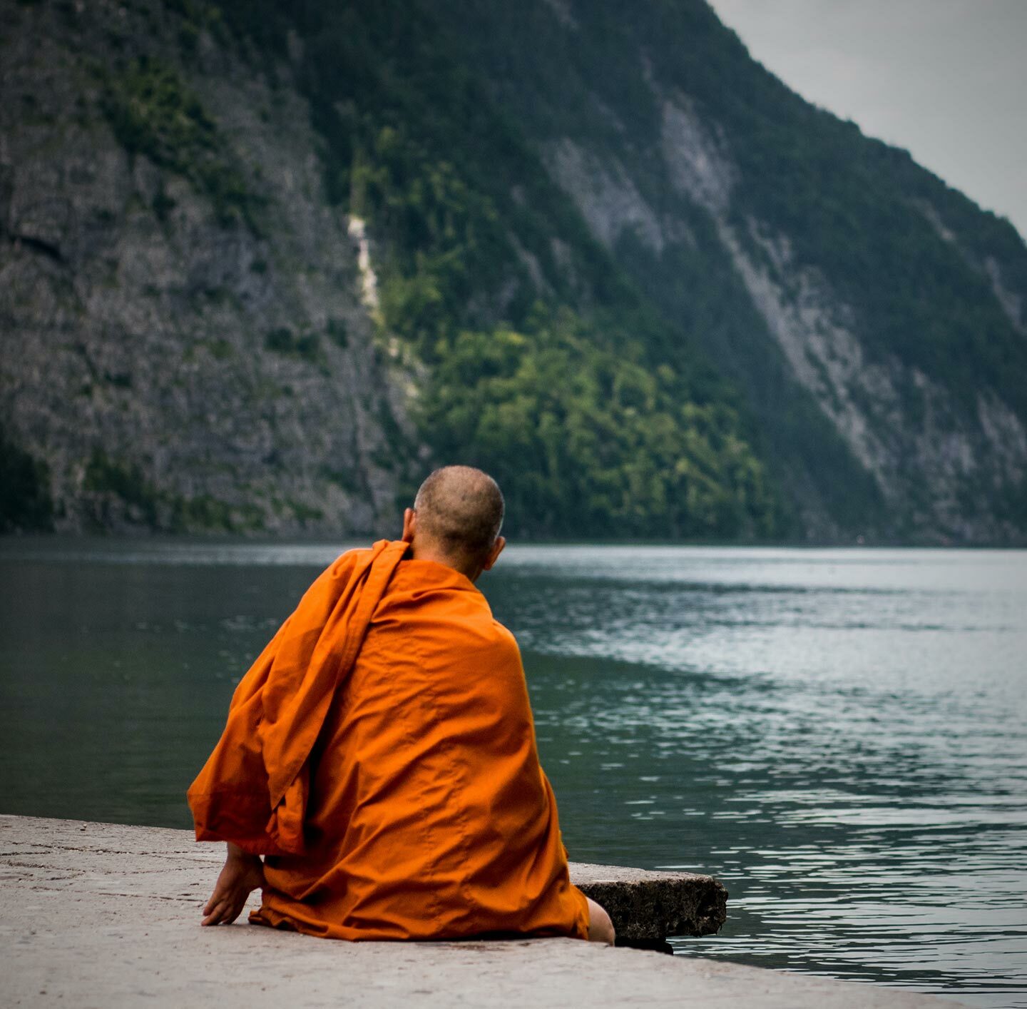 Buddhistischer Mönch sitzt am Flussufer