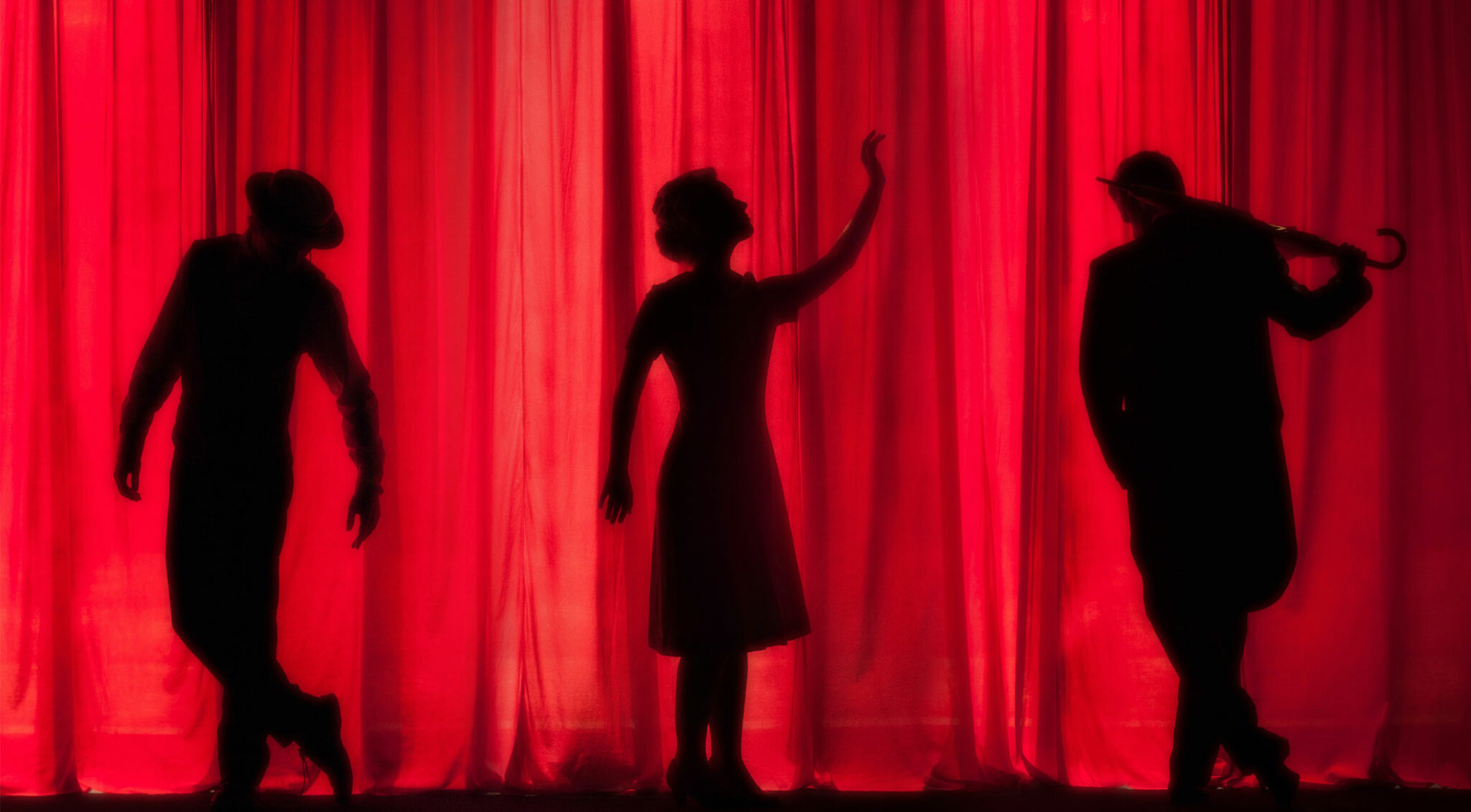 Silhouetten von Schauspielern vor einem Theatervorhang