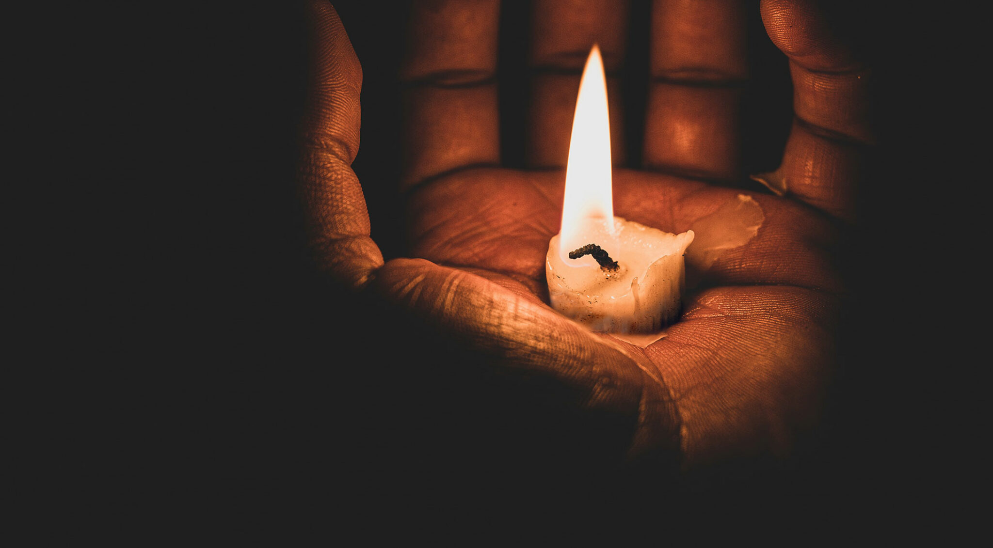 Eine Kerze brennt in einer Hand