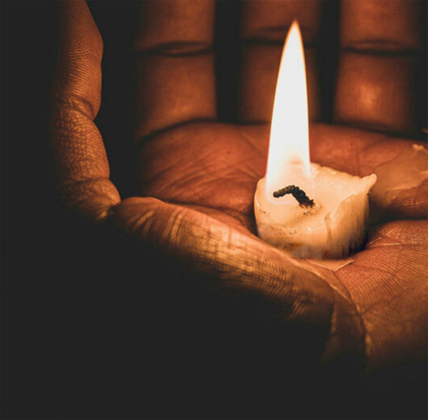 Eine Kerze brennt in einer Hand