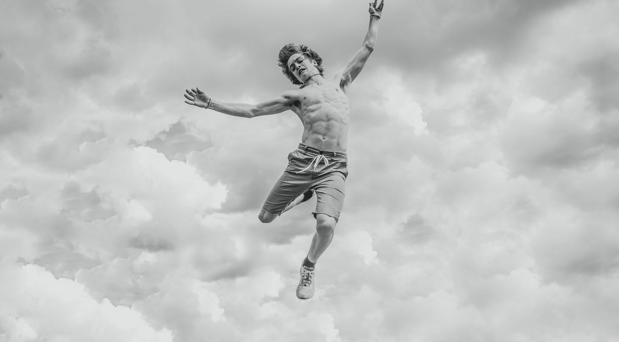 Ein junger Mann springt durch die Wolken