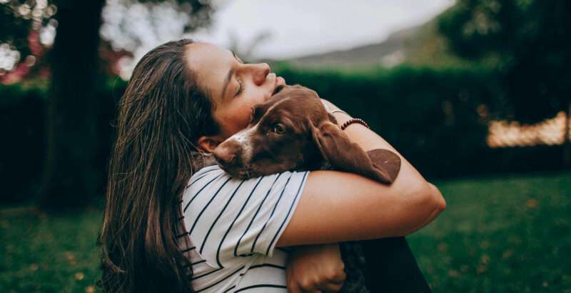 Frau hält den Hund in den Armen