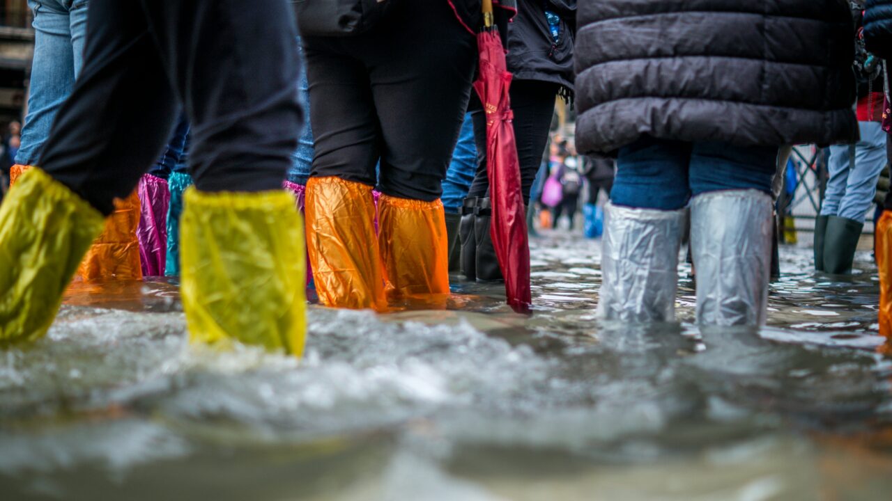 Menschen stehen mit Gummistiefeln im Wasser