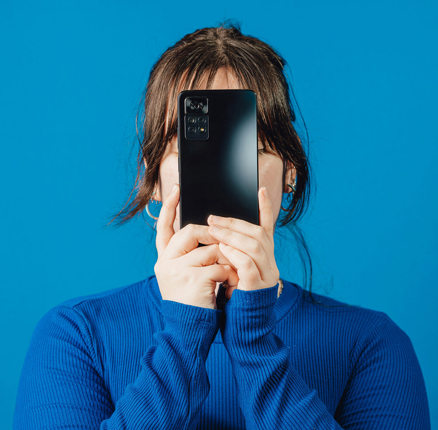 Junge Frau hält ein Smartphone vor ihr Gesicht