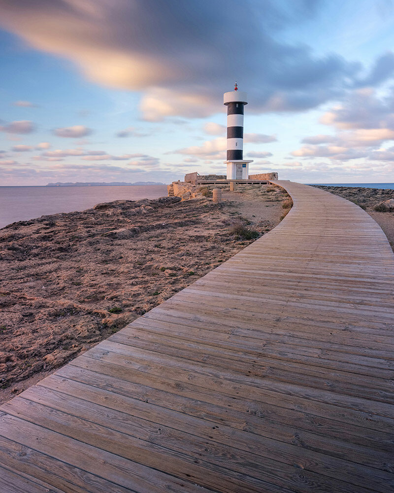 Ein Holzsteg, der zu einem Leuchtturm führt