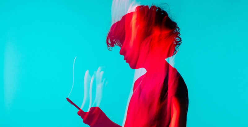 Rote Silhouette eines jungen Mannes mit Smartphone in der Hand vor türkisfarbenem Hintergrund