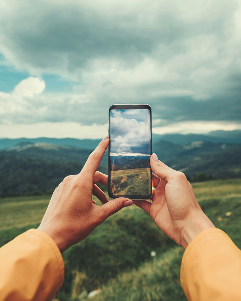 Blick auf eine Berglandschaft durch den Display eines Smartphones