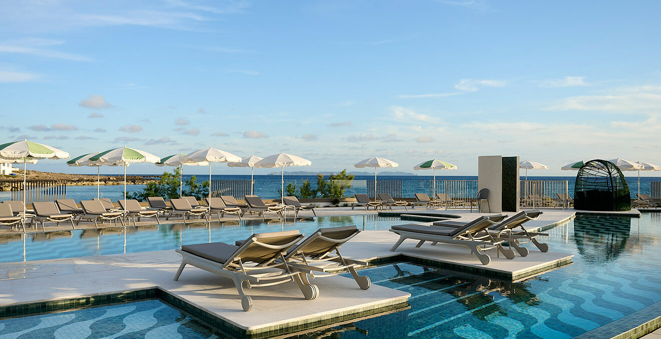 Blick auf die Poollandschaft des Hotels „Iberostar Selection Es Trenc mit geöffneten Sonnenschirmen