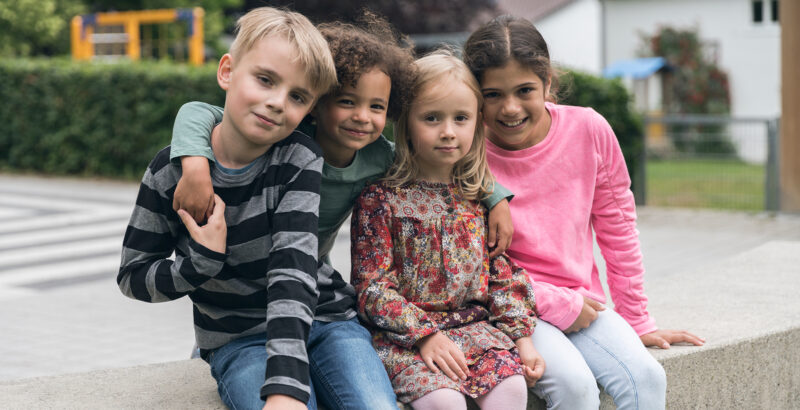 Vier Kinder unterschiedlicher Herkunft sitzen zusammen