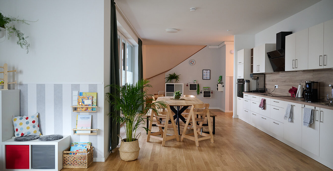 Moderner Gemeinschaftsraum mit Sofas, Tischen und Küchenzeile