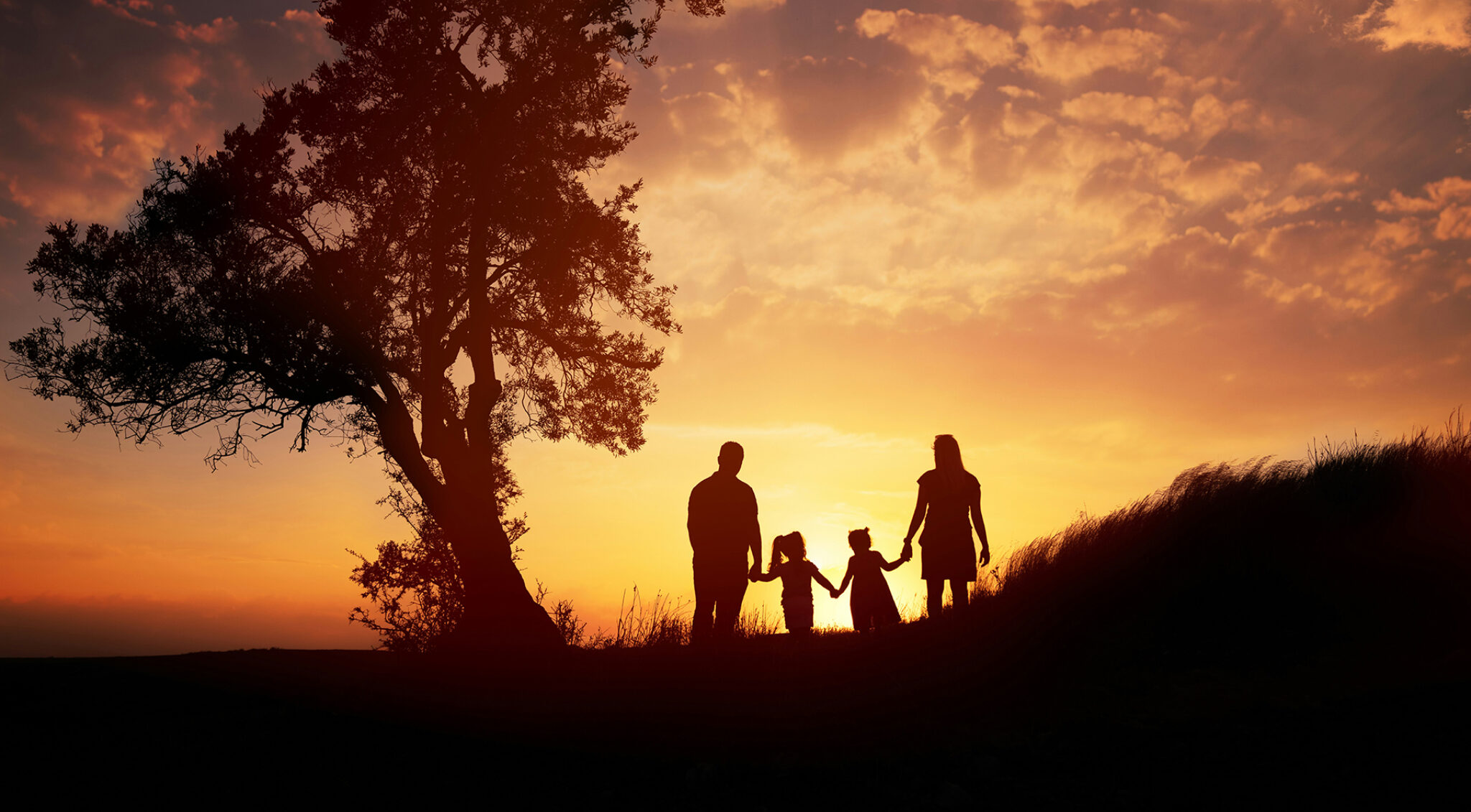 Silhouetten einer Familie im Gegenlicht bei Sonnenuntergang
