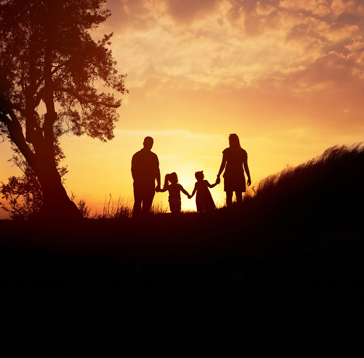 Silhouetten einer Familie im Gegenlicht bei Sonnenuntergang