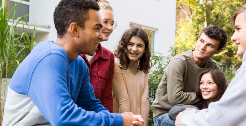 Mehrere junge Erwachsene sitzen zusammen, lachen und unterhalten sich.