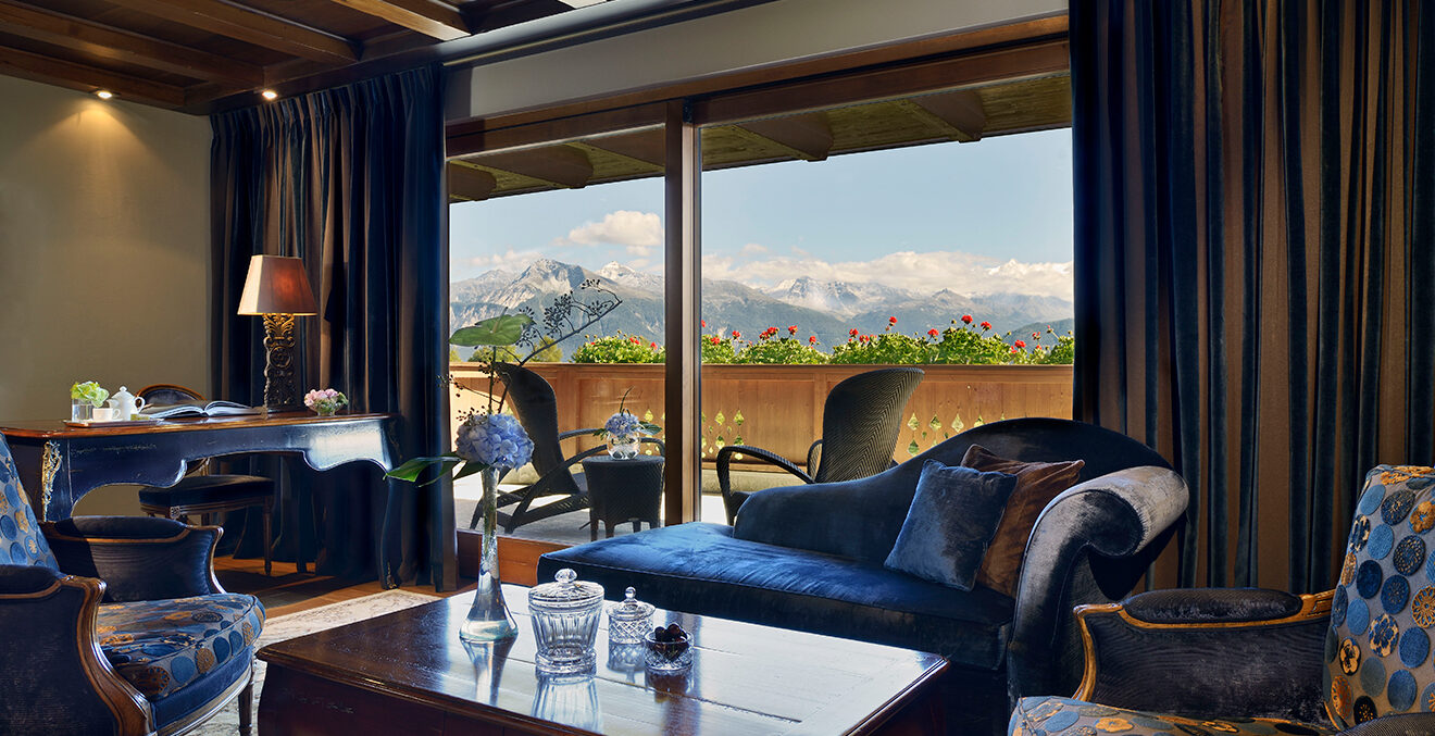 Modern eingerichtete Hotel-Lounge mit großen Fenstern und Blick auf die Berge.