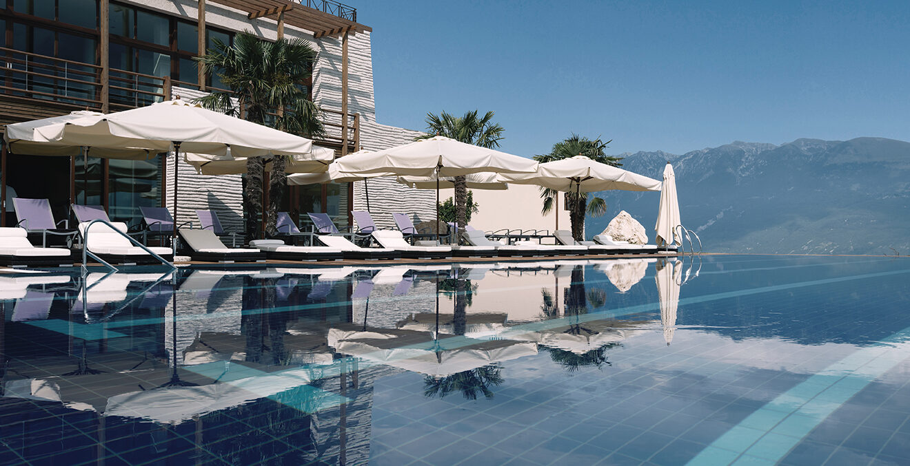 Infinity-Pool des Lefay Resort mit Blick auf den See und die umliegenden Berge, spiegelglatte Wasseroberfläche.“