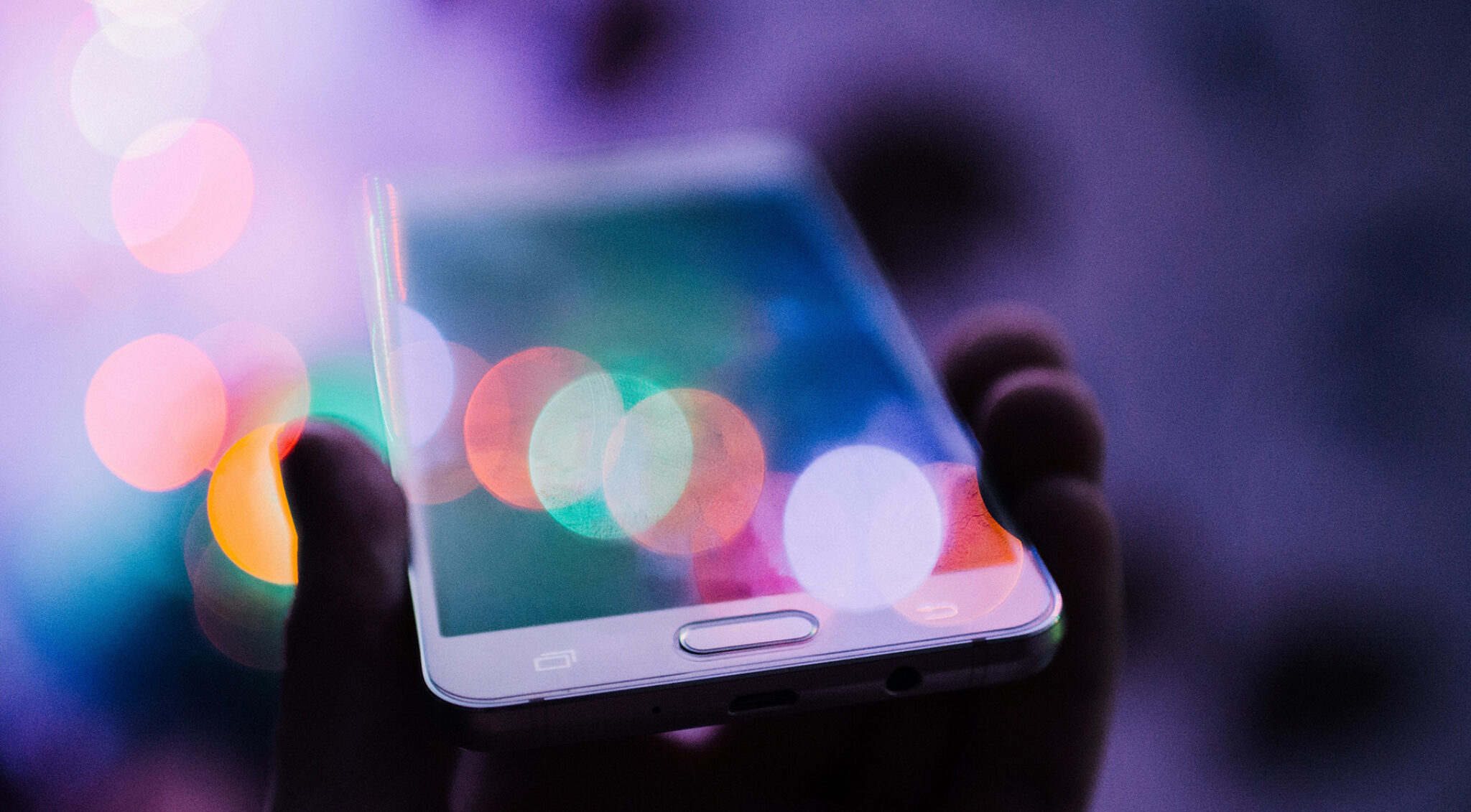 Unscharfe, bunte Lichtkreise auf dunklem Hintergrund symbolisieren digitale Ablenkung und Reizüberflutung durch Bildschirme.