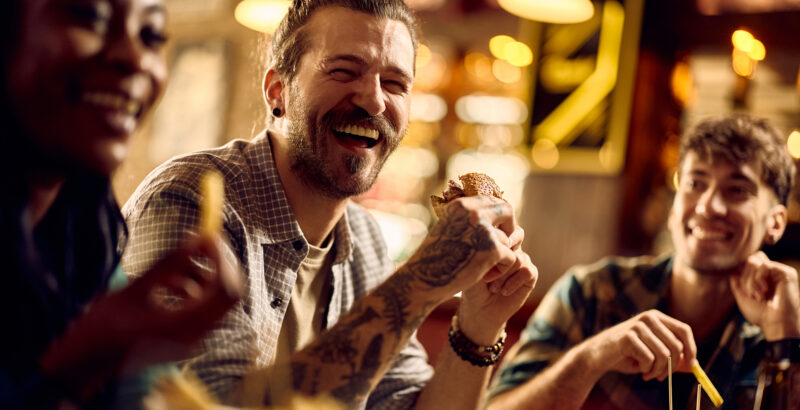 Freunde sitzen lachend in einem Café und unterhalten sich – Symbol für soziale Nähe ohne digitale Ablenkung.