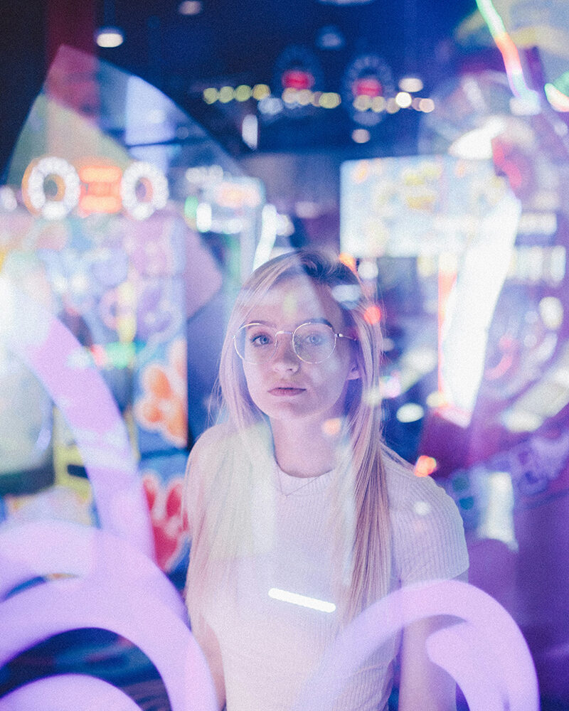Junge Frau in einem unscharfen Büro- oder Konferenzraum – Darstellung von Teamarbeit und Integration von KI in den Arbeitsalltag.