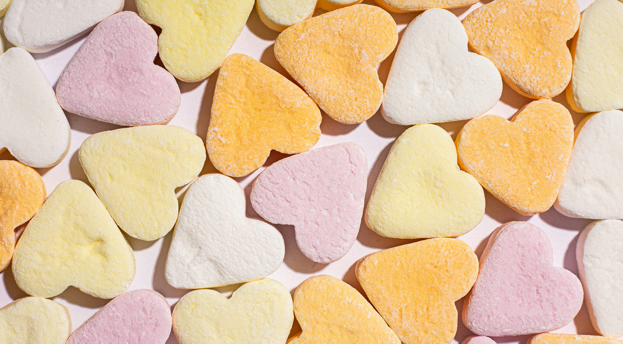 Bunt gemischte herzförmige Marshmallows in Pastellfarben als Hintergrundmotiv.