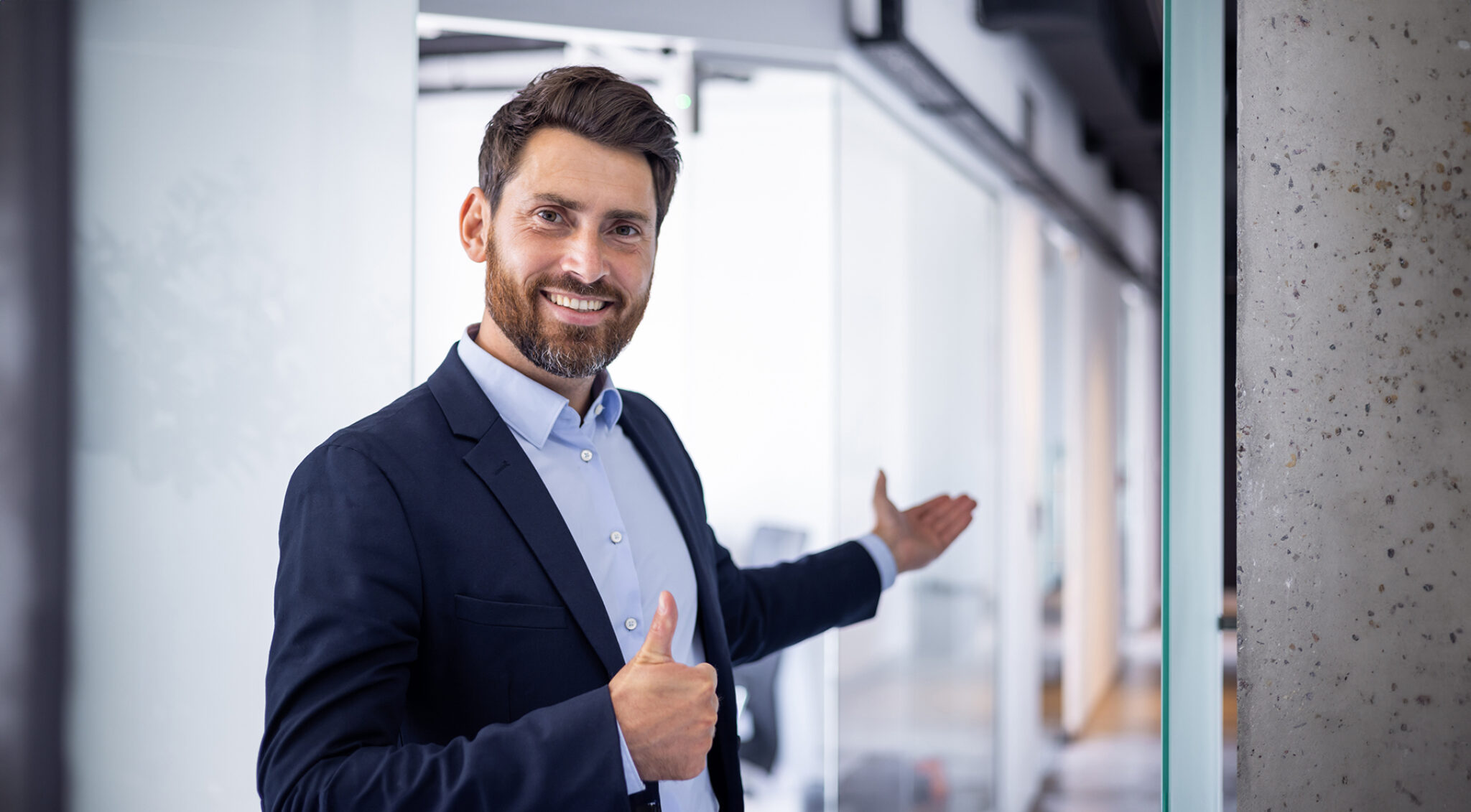 Porträt eines lächelnden Mannes im Business-Outfit vor einer modernen Büroarchitektur.