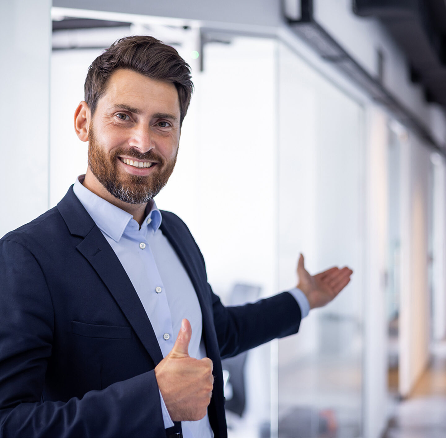 Porträt eines lächelnden Mannes im Business-Outfit vor einer modernen Büroarchitektur.