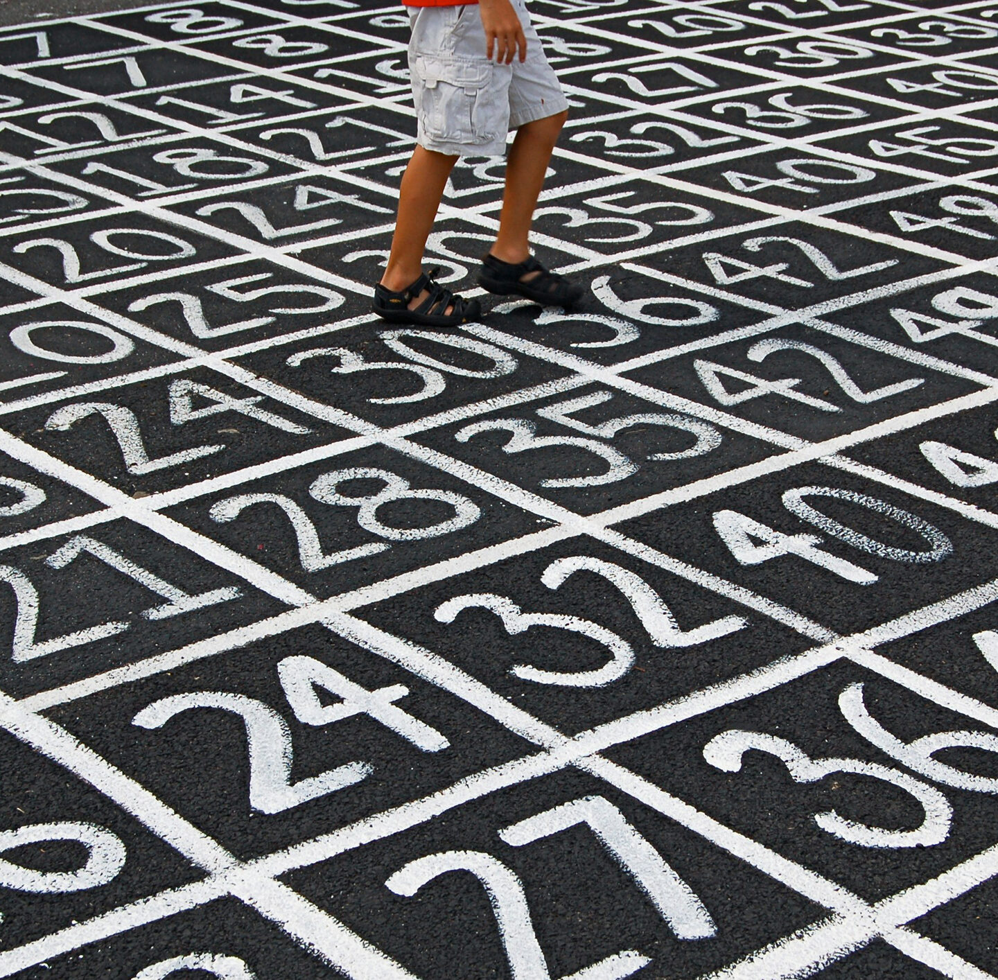 Person, deren Beine und Füße zu sehen sind, läuft über einen Boden mit großflächigem schwarz-weißem geometrischem Muster.