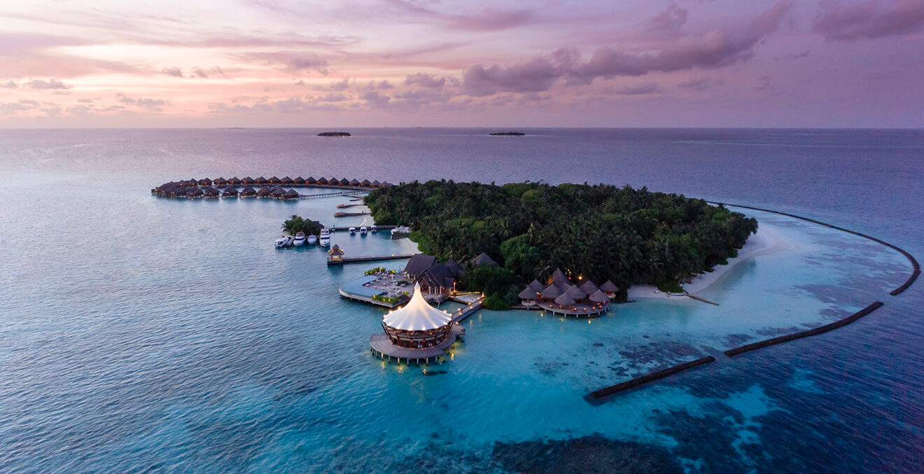 Sonnenuntergang mit rosafarbenem Himmel über einer tropischen Inselgruppe.