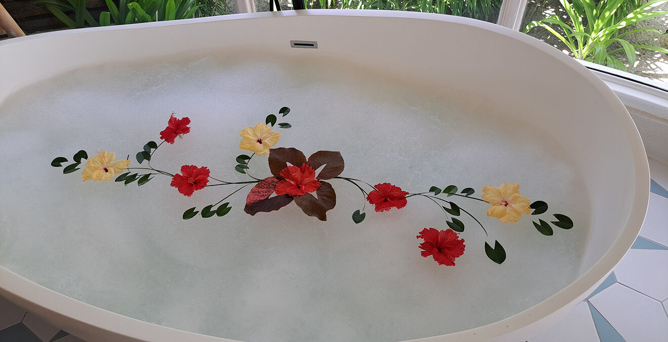 Weisse Badewanne mit Wasser und echten Blumen.