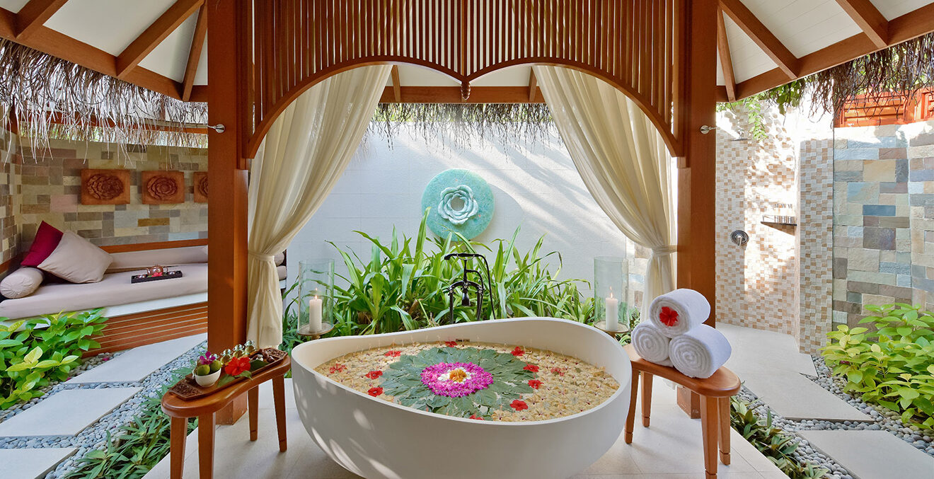 Freistehende Badewanne mit Blüten unter einem Baldachin.