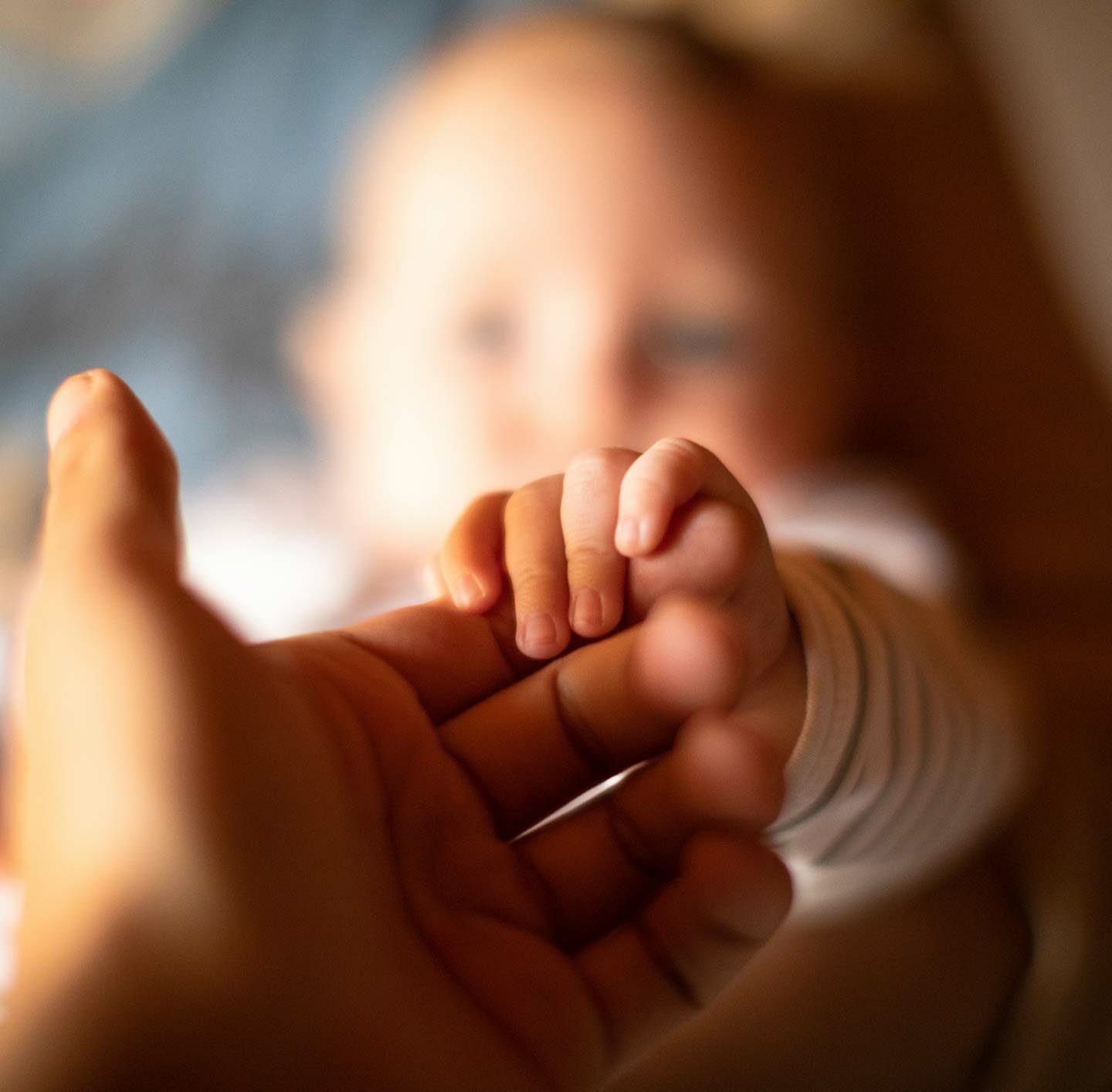 Ein Baby greift mit seiner Hand den Finger eines Erwachsenen – Symbol für Vertrauen, Fürsorge und Weitergabe von Werten.