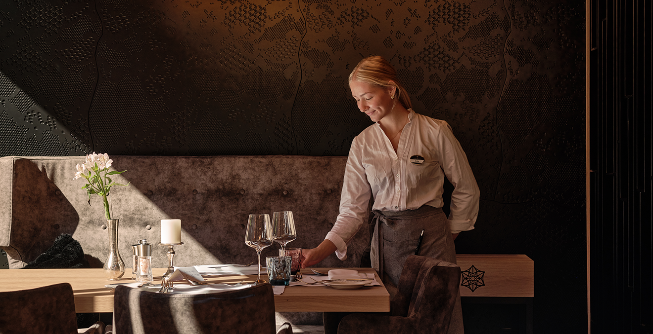 Junge Frau kontrolliert den schön eingedeckten Tisch eines Restaurants.