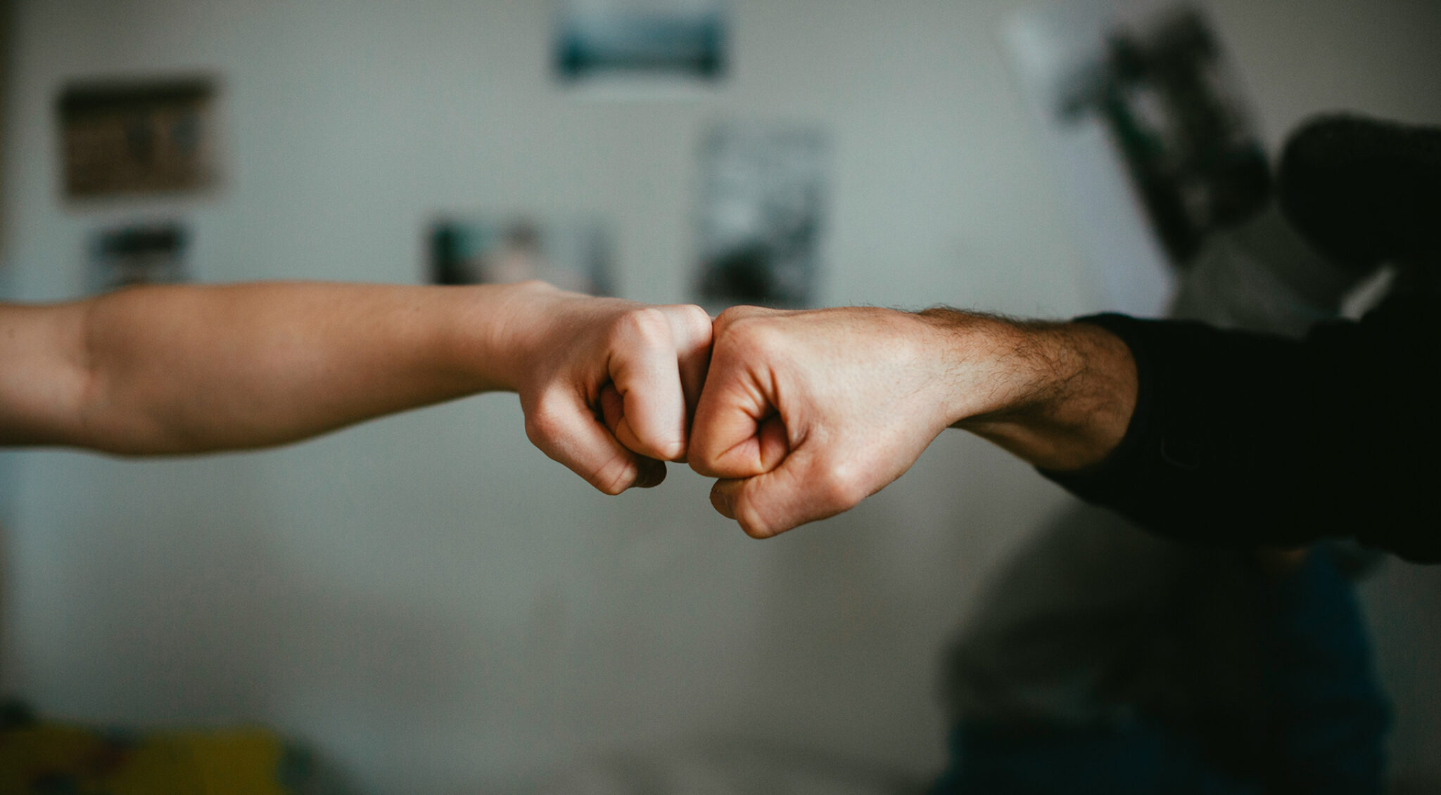 Zwei Personen stoßen zur Begrüßung oder Zusammenarbeit ihre Fäuste an.