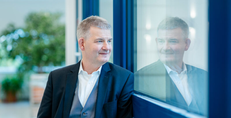 Johannes Wallacher vor hellem Hintergrund, das Bewegung und Unschärfe zeigt.