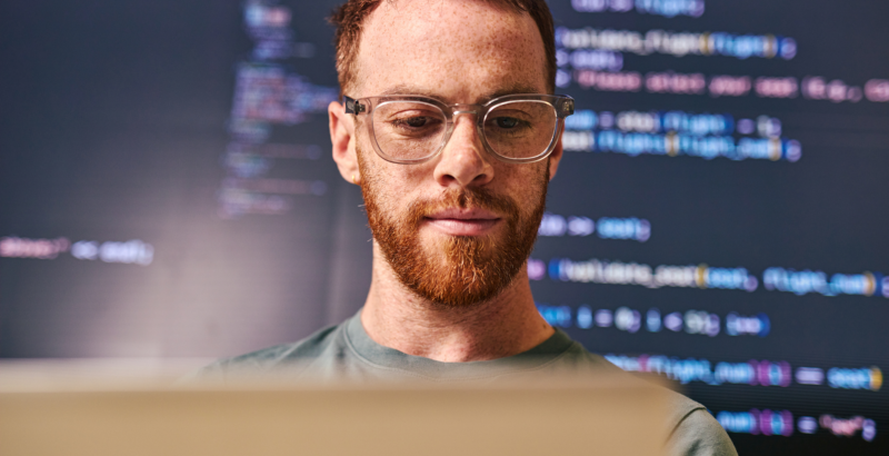 Nahaufnahme eines männlichen Gesichts mit digitaler Verzerrung im Mundbereich vor einem Bildschirmhintergrund.