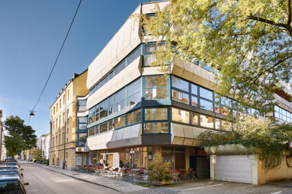 Die Hochschule für Philosophie in München – ein modernes Gebäude mit Glasfassade und begrüntem Außenbereich bei Tageslicht.