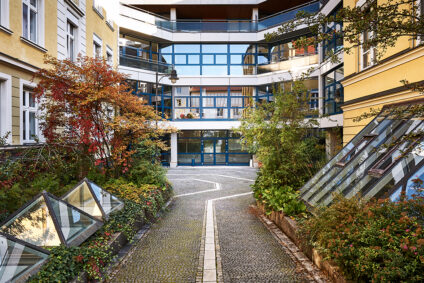 Die Hochschule für Philosophie in München – ein modernes Gebäude mit Glasfassade und begrüntem Außenbereich bei Tageslicht.