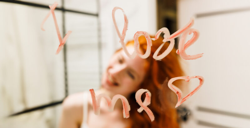 Nahaufnahme eines Gesichts hinter einer Glasscheibe, auf die Wörter und Zahlen geschrieben sind.