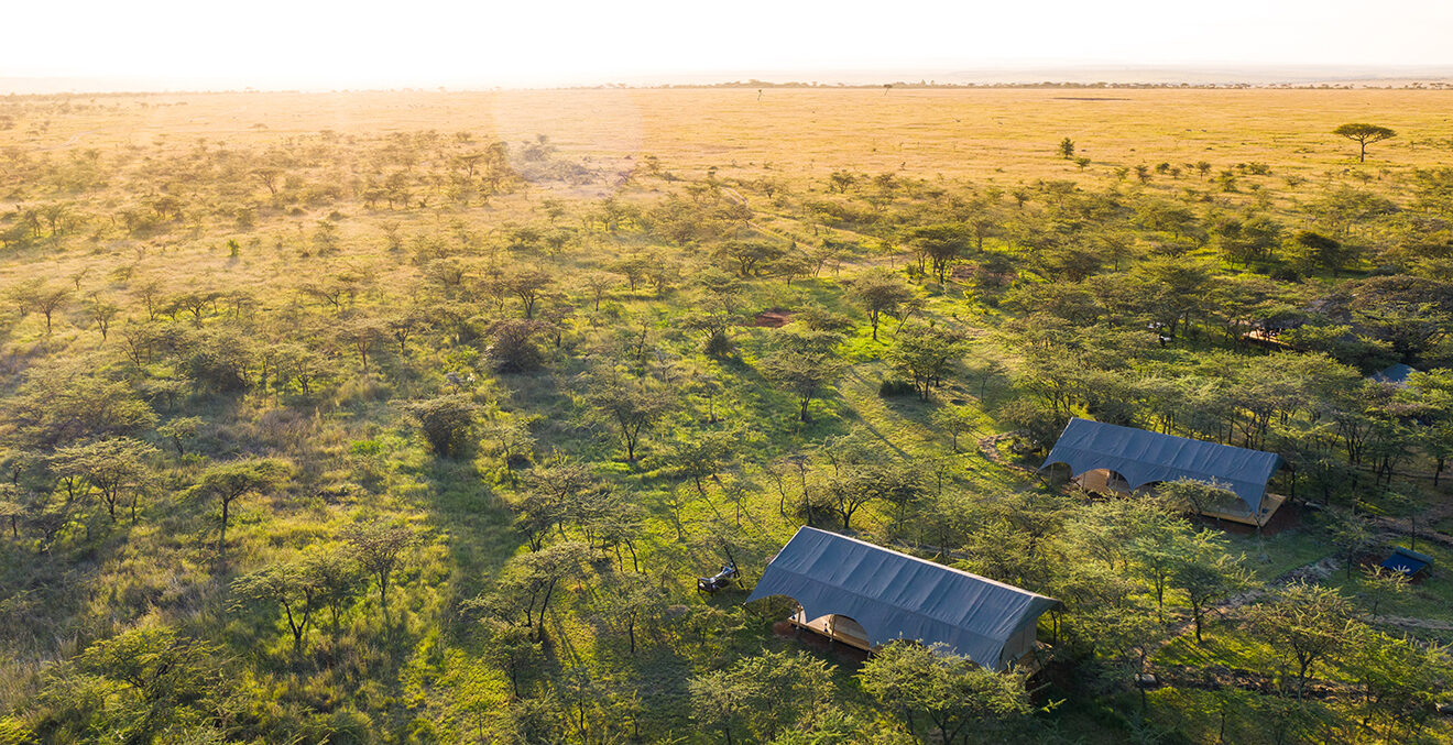 Luftaufnahme einer weiten Landschaft, Häusern und grünen Vegetationsflächen.