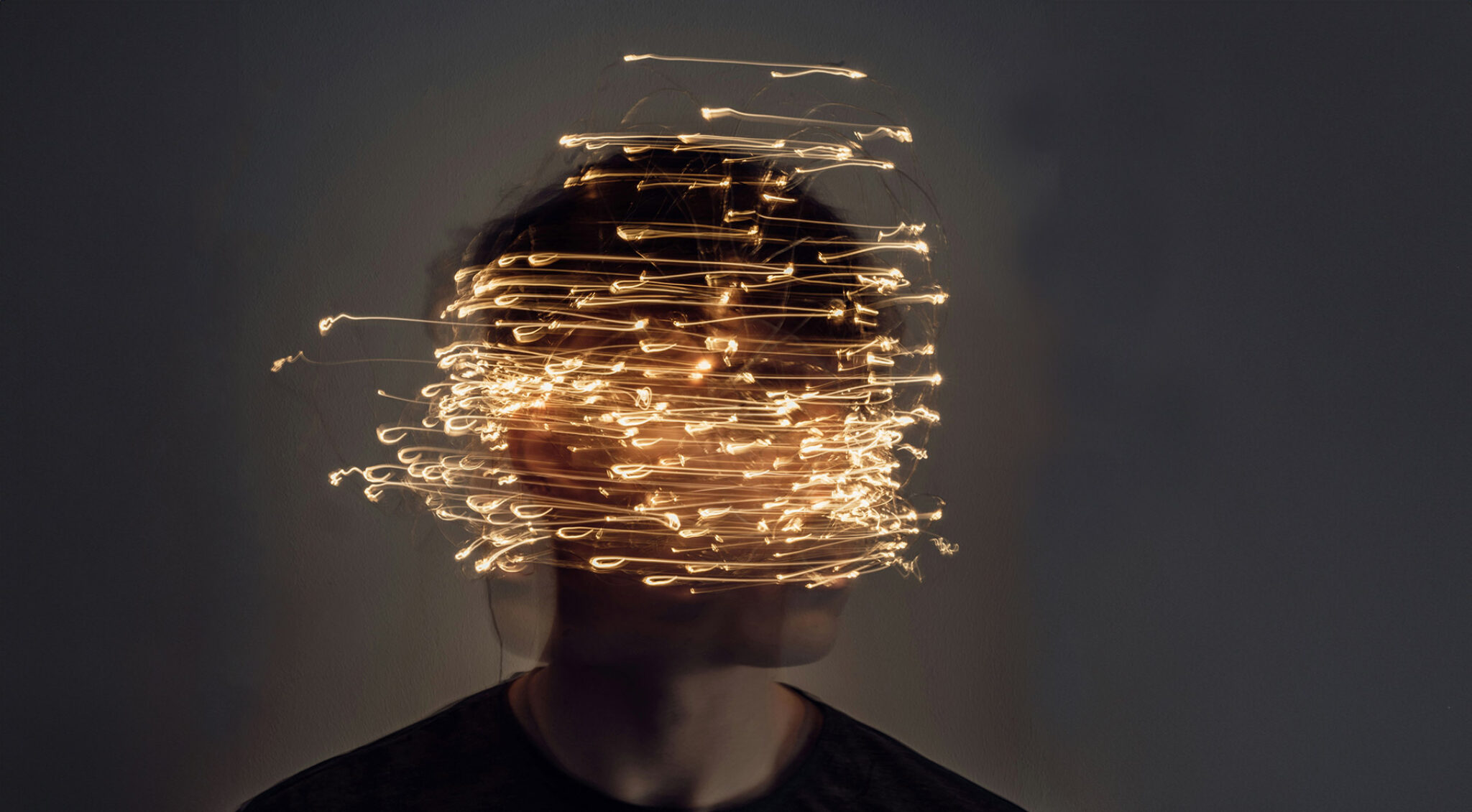 Porträt einer Person mit goldenen Lichtspuren vor dem Gesicht.