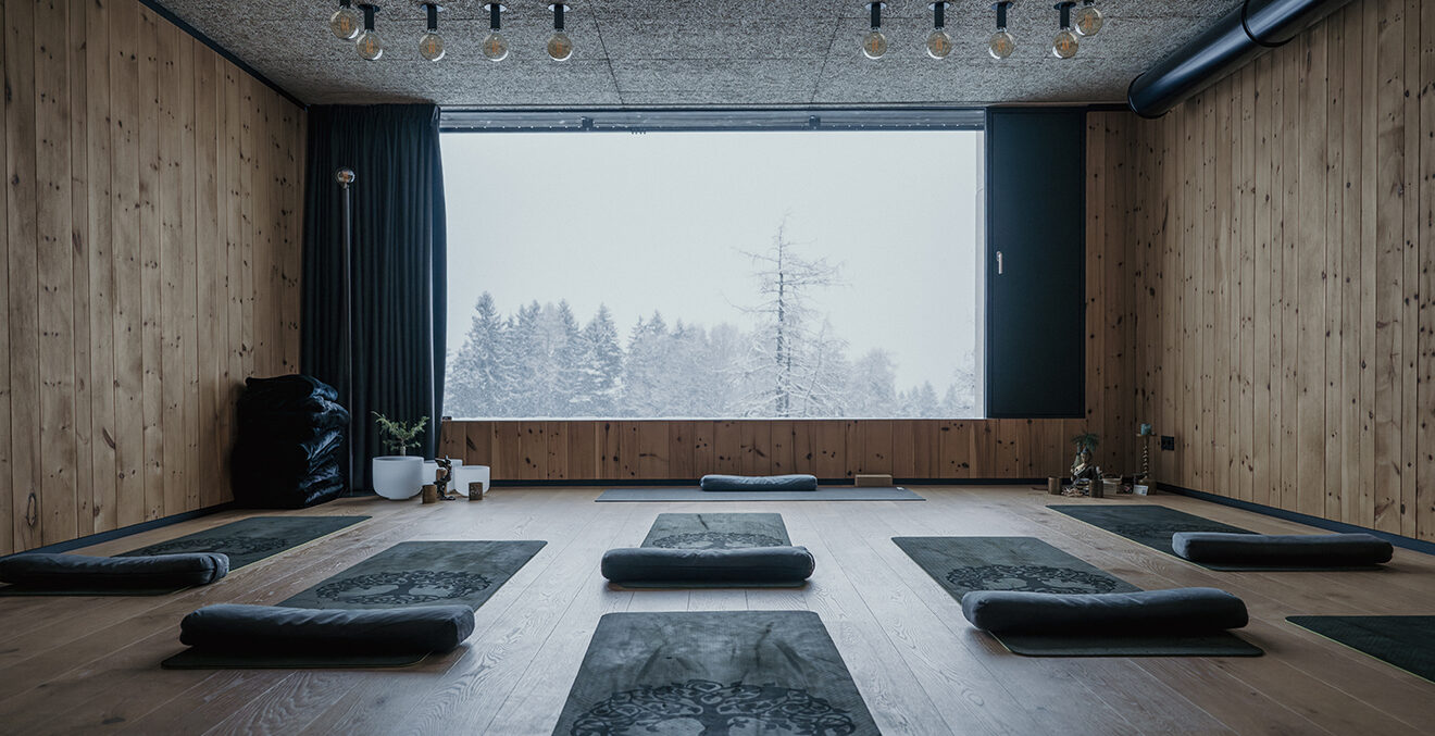Yogaraum mit großem Panoramafenster und heller Holzvertäfelung.